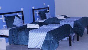 A room with two beds, each with a headboard, and a small white nightstand. - ELAND ACCOMMODATIONS (Ongata Rongai)