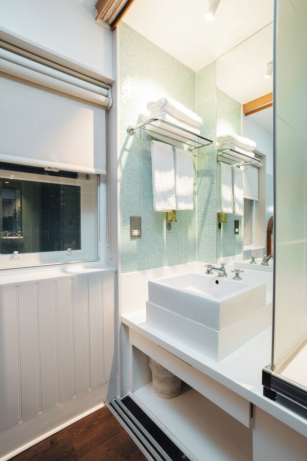 Un baño moderno con dos lavamanos, un espejo grande y una ventana con persianas.