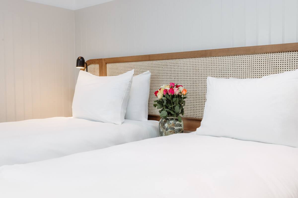 A neatly made bed with white linens and a wooden headboard.