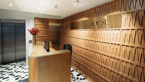 A reception area with a wooden panel wall, a reception desk, and an elevator. - Leicester House Hotel (London)