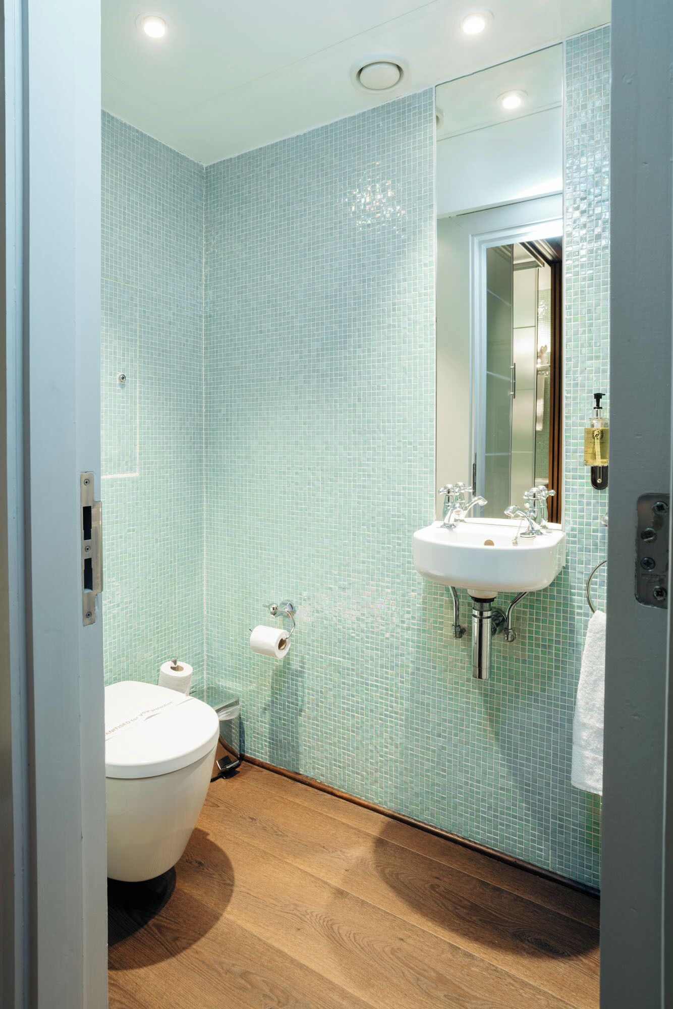 Een badkamer met toilet, wastafel en spiegel.