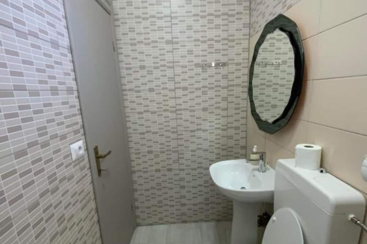 A small bathroom with a toilet, sink, and mirror.