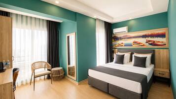 A modern hotel room with a large bed, a desk, a chair, and a painting on the wall.