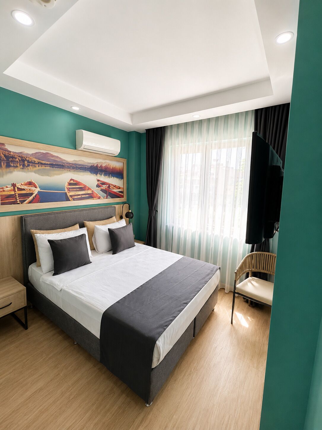 Una habitación de hotel moderna con una cama grande, un cuadro de barcos, un televisor y una silla.