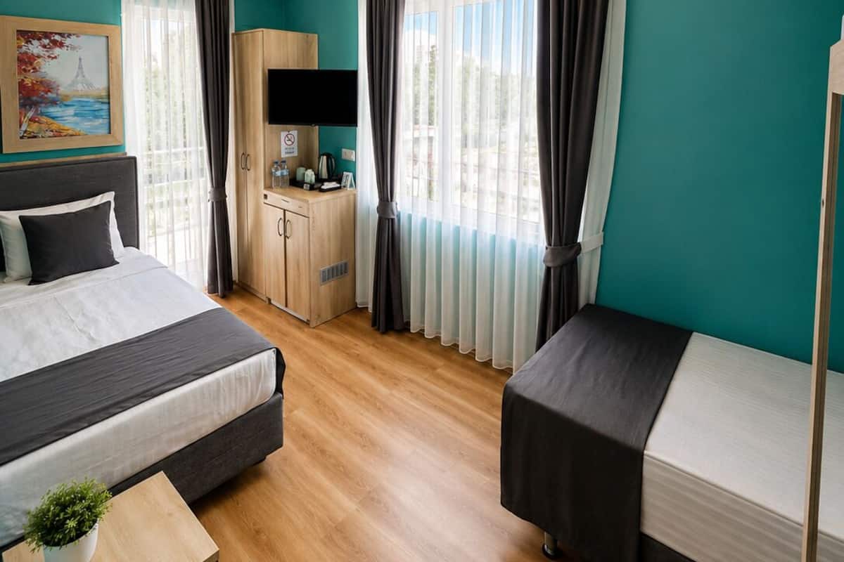 A modern hotel room with a bed, a desk, a wardrobe, and a TV.