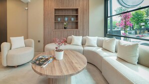 Un moderno vestíbulo de hotel con un sofá curvo, una mesa de centro de madera y una estantería.