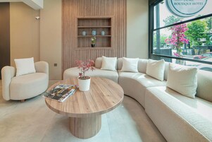 Un moderno vestíbulo de hotel con un sofá curvo, una mesa de centro de madera y una estantería.
