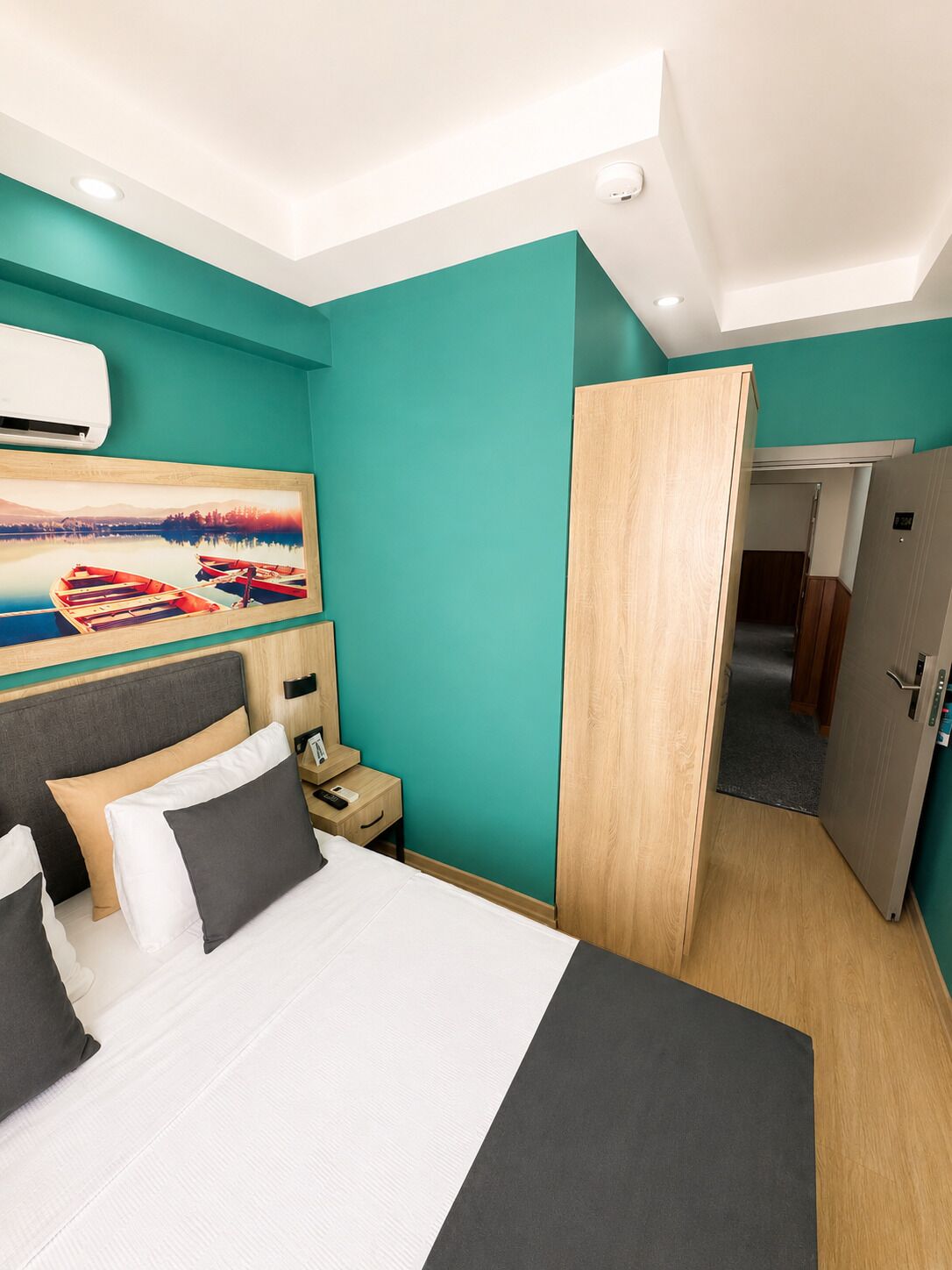 Une chambre d’hôtel avec un lit, une table de chevet, un tableau et une armoire.