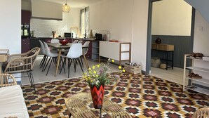 Een moderne woonkamer met een kamer met een patroon vloer, een eethoek met stoelen en een tafel, een keuken op de achtergrond, en een trap naar een ander niveau.