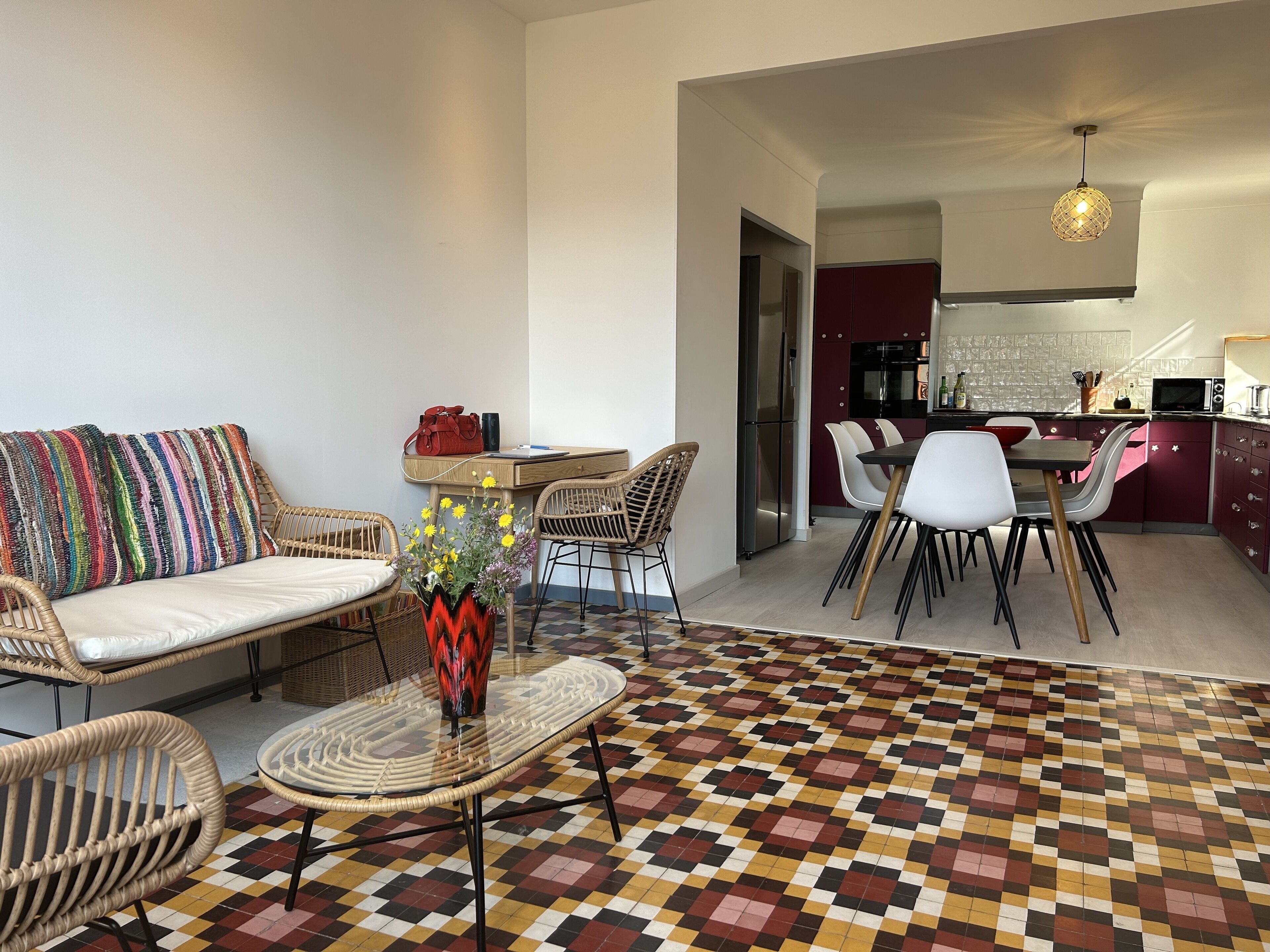 A modern living room with a sofa, chairs, a dining table, and a kitchen area with cabinets and appliances.