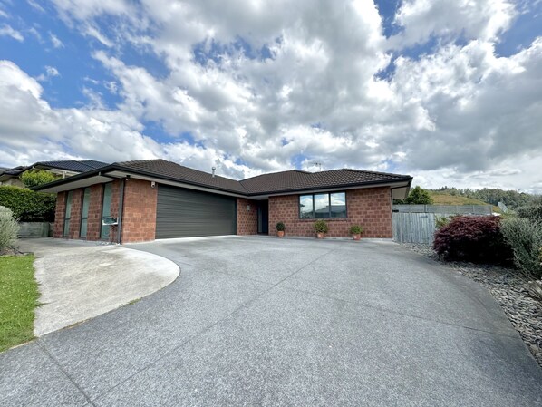 A two-story house with a garage, a driveway, and a well-maintained lawn.