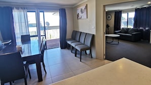 Una sala de estar moderna con un sofá, una mesa de comedor con sillas y un balcón con vistas.