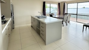 Una cocina moderna con una isla central, un comedor con vistas al mar y un ventanal grande.