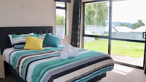 Un dormitorio con una cama grande, una mesita de noche, una ventana con cortinas y vistas al exterior.