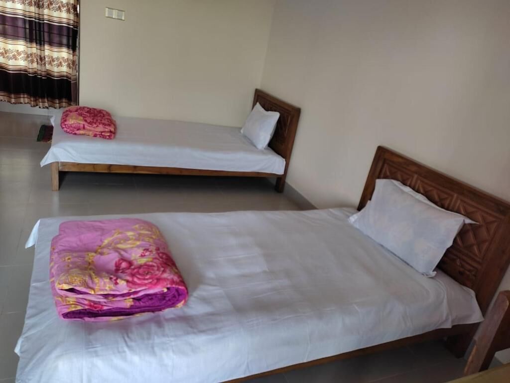 Two single beds with wooden headboards in a room with plain walls and a tiled floor.