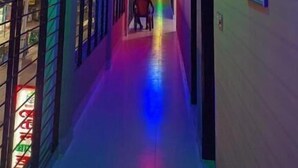 A hallway with a rainbow light strip on the floor, leading to a door at the end. - Hotel Grand Brothers (Sylhet)