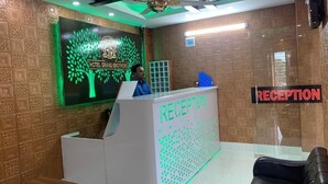 A reception area with a reception desk labeled "RECEPTION" and a sign indicating "RECEPTION" in red letters. - Hotel Grand Brothers (Sylhet)