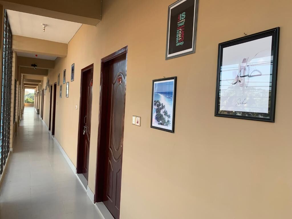 A hallway with framed pictures on the walls, a wooden door, and a tiled floor.