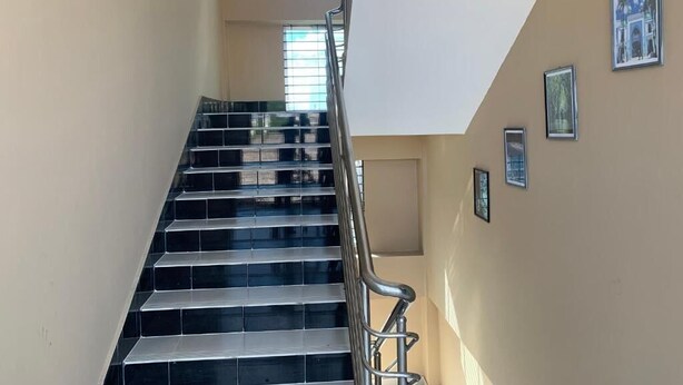 A staircase with black steps and a metal railing, leading to an upper floor. - Hotel Grand Brothers (Sylhet)