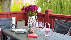A table set outdoors with a vase of purple flowers, wine glasses, plates, and a box of chocolates. - fewo1846 - Suite Royal - elegant old building apartment with balcony (Flensburg)