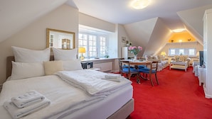 A hotel room with a large bed, a desk, a chair, and a red carpet. - fewo1846 - Villa Royal (Flensburg)