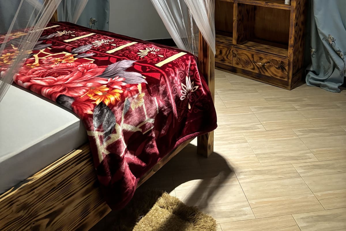 Un dormitorio con cama con dosel, un armario de madera y una colcha con motivos florales.