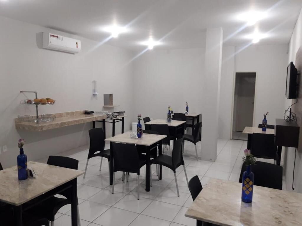 A dining area with tables and chairs, a counter with a display of fruits, and a wall-mounted air conditioner.