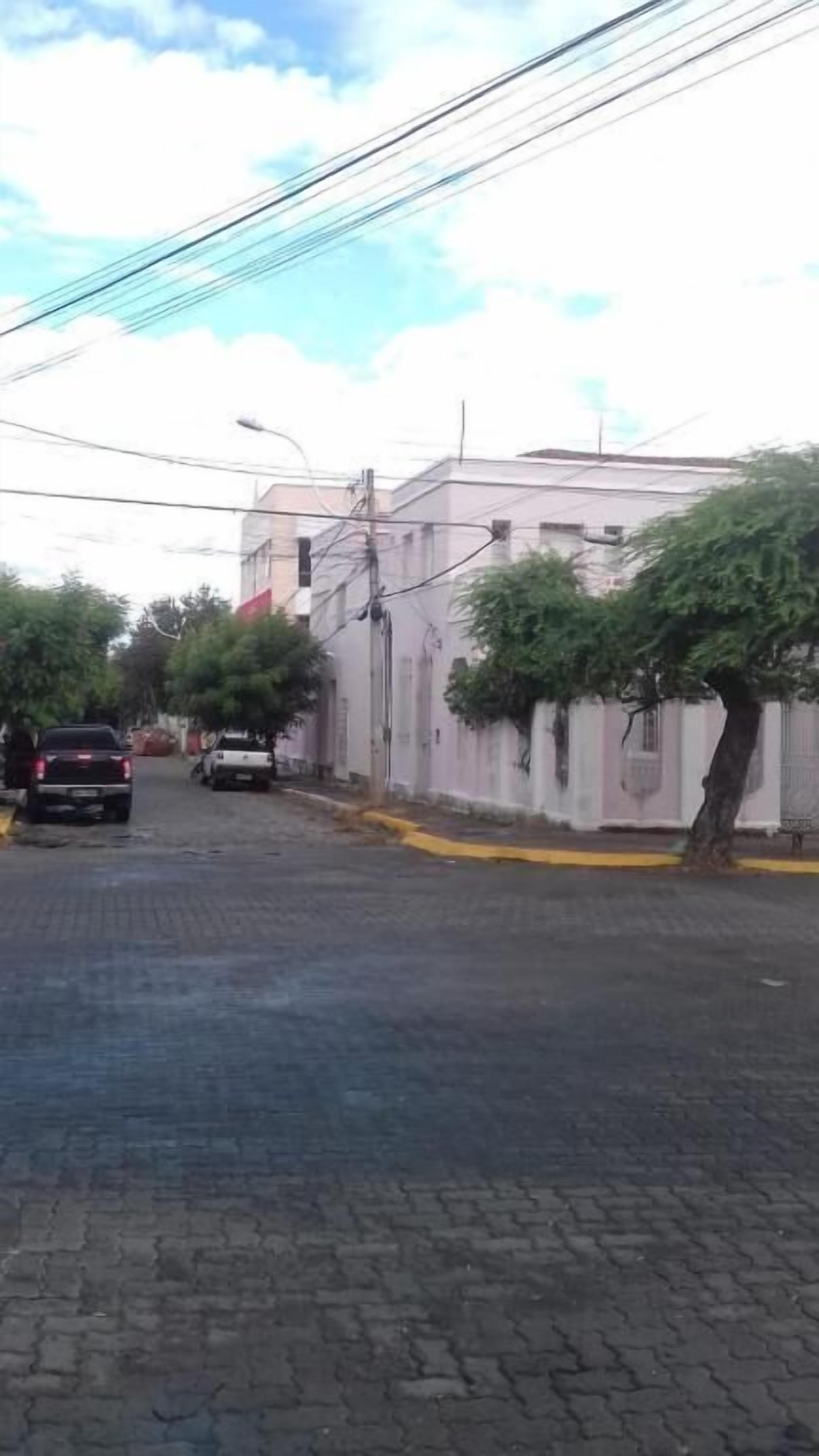 Una calle pavimentada con edificios a un lado y árboles al otro.