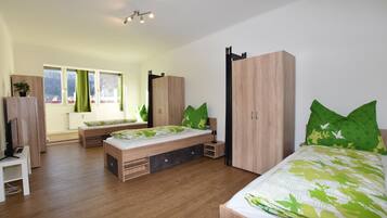 Ein modernes Schlafzimmer mit Holzboden, einem Bett mit grüner Bettwäsche, einer Bank, einem Kleiderschrank und einer Heizung.
