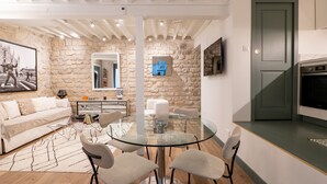 A modern living room with a stone wall, a glass dining table, and a minimalist design. - A Story in Stone, by Veeve (Paris)