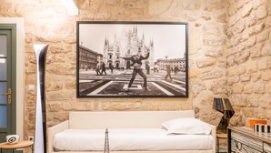 A room with a stone wall, a framed black and white photo, a white sofa, a glass coffee table, and a modern lamp. - A Story in Stone, by Veeve (Paris)