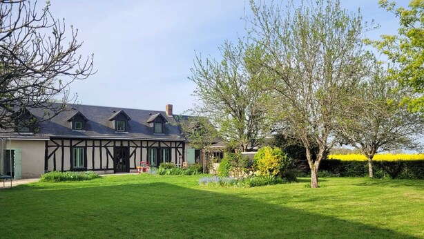 Een huis in traditionele Tudorens stijl met een verzorgd gazon en tuin.