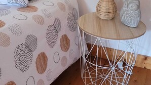 Een slaapkamer met een bed, een rond nachtkastje met een lamp en een decoratief uilenbeeld.