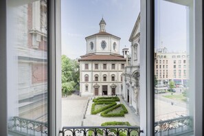 Blick auf ein Gebäude mit einer zentralen Kuppel und symmetrischen Fenstern, umgeben von einem gepflegten Garten.