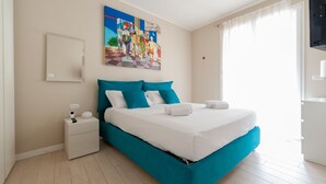 Una camera da letto con un letto, un comodino, un quadro e una finestra.