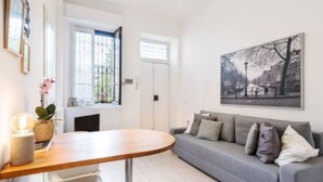Una sala de estar moderna con un sofá gris, una mesa de centro de madera y un cuadro de un paisaje urbano en la pared.