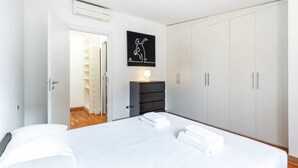 A bedroom with a bed, a dresser, a wardrobe, and a wall-mounted artwork.