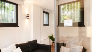 Ein modernes Wohnzimmer mit einem schwarzen Ledersofa, weißen Kissen, einer Glastrennwand und einem Schild, das anzeigt, dass die Unterkunft von EasyLife verwaltet wird.