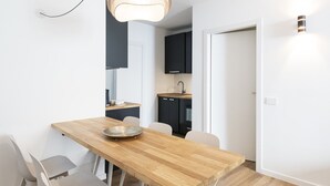 Eine moderne Küche mit dunklen Schränken, einem Holzessttisch und einer Pendelleuchte.