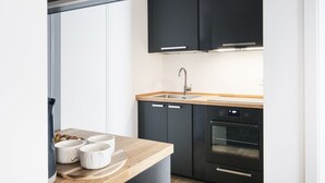 Eine moderne Küche mit dunklen Schränken, einer Holzauskleidung, einer Edelstahl-Spüle und einem Backofen.