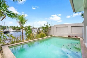 A swimming pool with a view of boats and marina in the background.