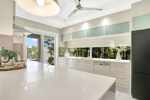 A modern kitchen with a large island, built-in appliances, and a view of greenery outside.