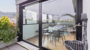 Un comedor moderno con pared de vidrio, una mesa dispuesta con sillas y vistas a la ciudad.