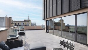 Une terrasse sur le toit, dotée d’un espace extérieur aménagé, de grandes fenêtres et offrant une vue sur le panorama urbain.