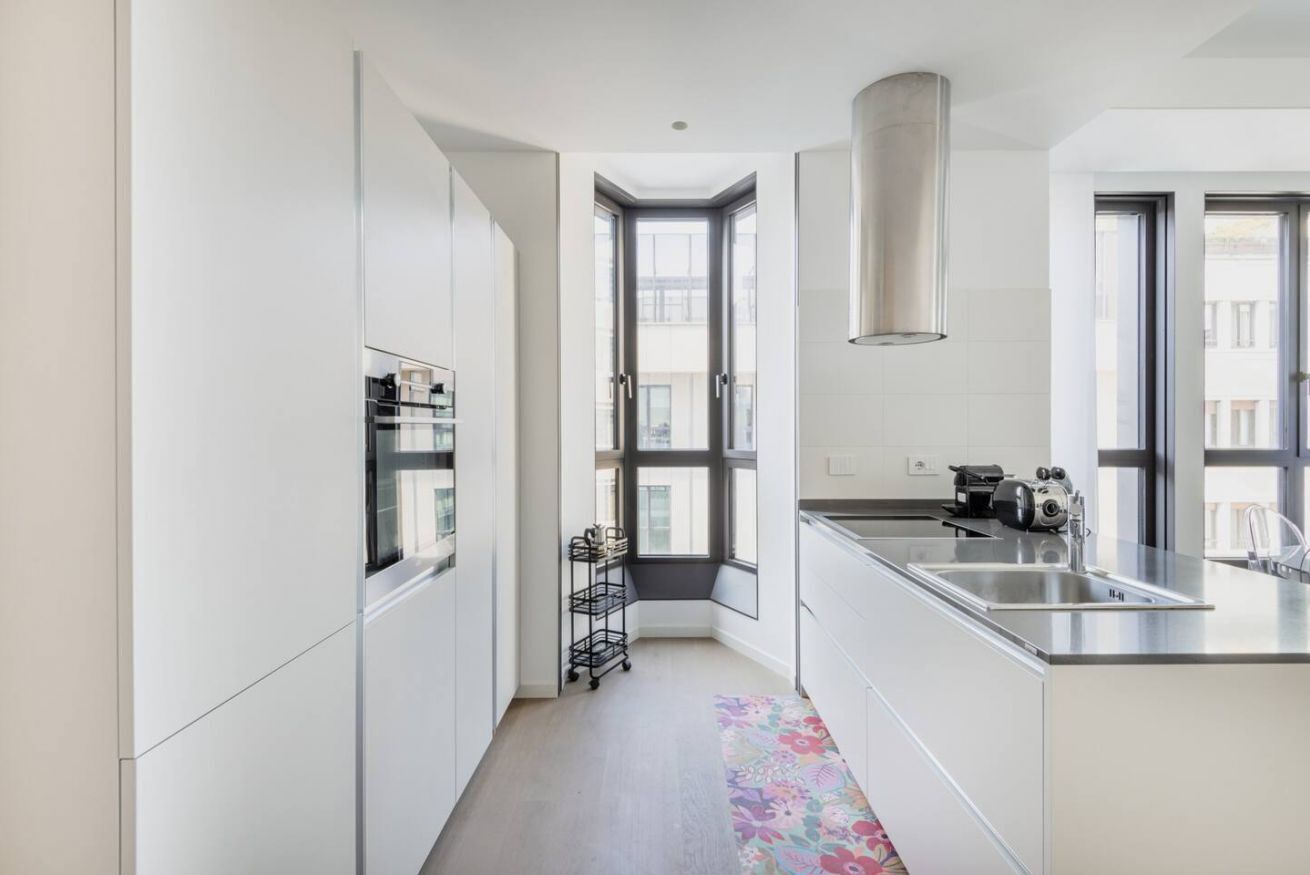 Eine moderne Küche mit weißen Schränken, einer Edelstahlspüle und einem Fenster mit Blick auf die Stadt.
