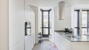 Une cuisine moderne avec des meubles blancs, un évier en acier inoxydable et une fenêtre donnant sur la ville.