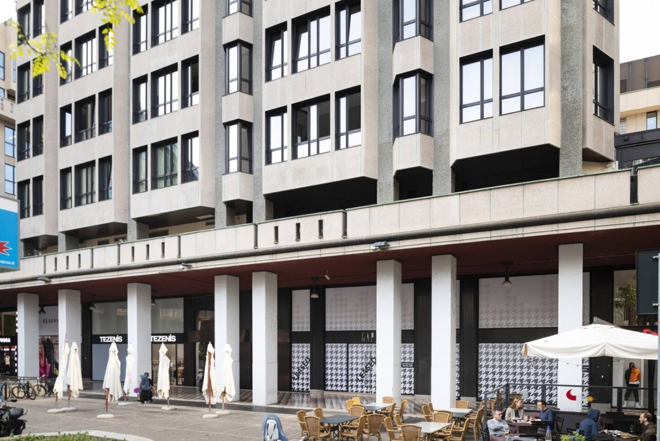 Ein mehrgeschossiges Gebäude im modernen Architekturstil, mit großen Fenstern und einem zentralen Atrium mit Sitzbereichen.