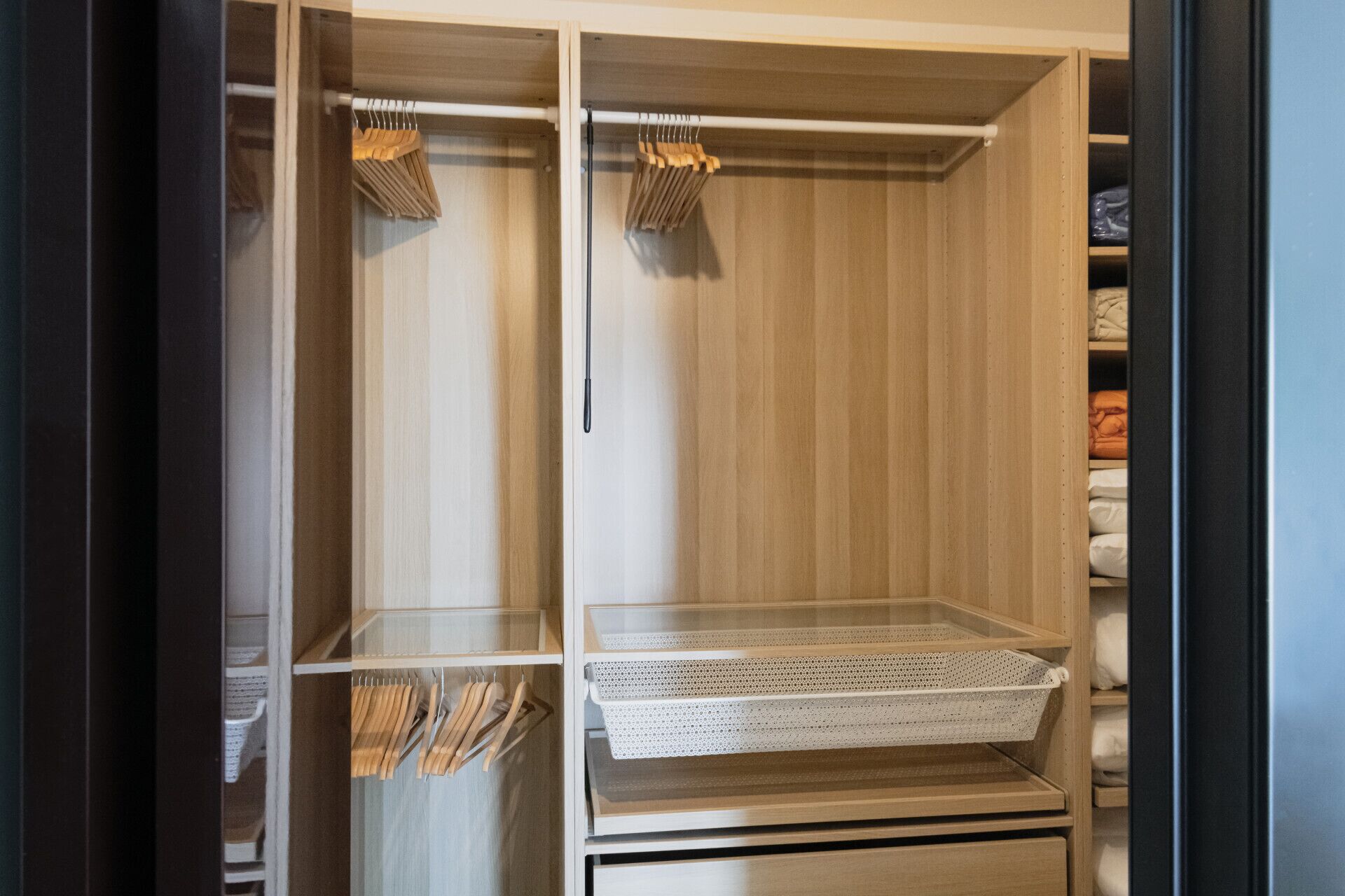 A walk-in closet with wooden shelves, a hanging rod, and a basket.