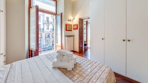 A bedroom with a large bed, a wardrobe, and a view of the street through an open door. - Easylife - Refined apartment in Viale Montegrappa, 18 (Milano)