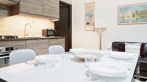 A modern kitchen with a dining area, featuring a white table set for four, a microwave, and a stove.